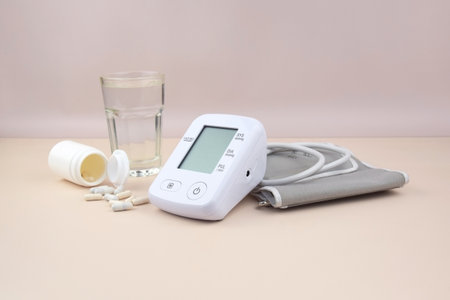Digital blood pressure tonometer and pack of pills on a light background with copy space. Healthcare...