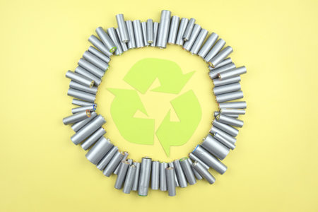 Used AA batteries and proper disposal of environmentally and soil-toxic batteries on a green background. The concept of processing harmful and recyclable objects.の写真素材