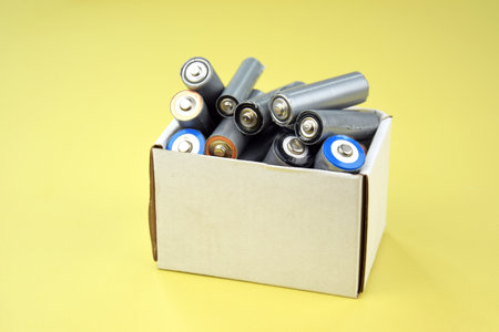 Used AA batteries and proper disposal of environmentally and toxic batteries on a green background.の写真素材