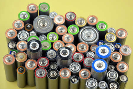 Used AA batteries and proper disposal of environmentally and soil toxic batteries on a green background.の写真素材