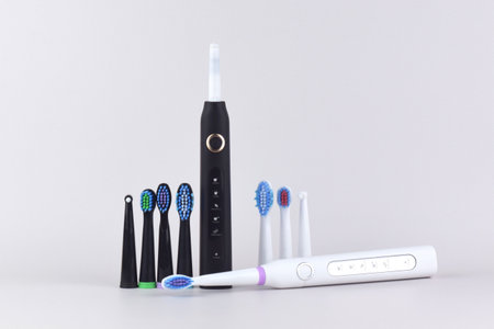 Modern electric ultrasonic toothbrush with rechargeable battery on a gray surface. Teeth care.