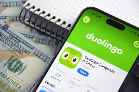 Kharkiv, Ukraine, 7 August 2026: Duolingo app on the smartphone iPhone 15 screen and money.