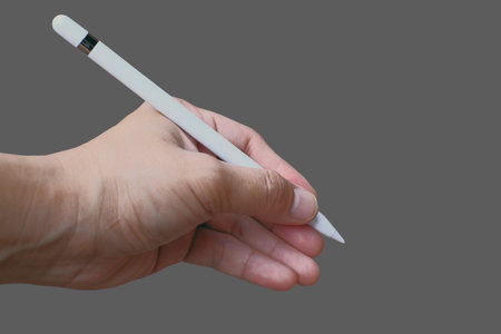The white smart pen that use with tablet was hold by left hand on isolate grey backgroundの写真素材