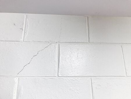 The white brick wall cracked. Wall damage.