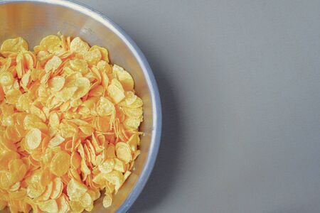 Top view of cereal in the stainless bowl with gray color tile background. Snack preparation for kid.の写真素材