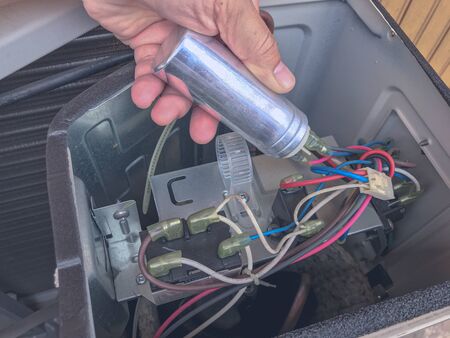 Air conditioner repair by technician. The technician replace the capacity run of airconditionaerの写真素材