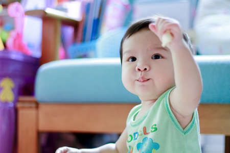 Portrait of cute asian toddler boy while he eating some snack. Portrait cute asian baby with blurred...