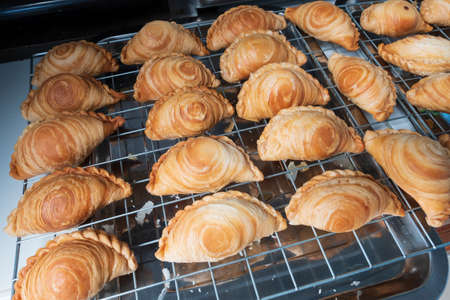 Curry puff. Close up the curry puff stack on the strainer after fried. Asian food cuisine.の写真素材