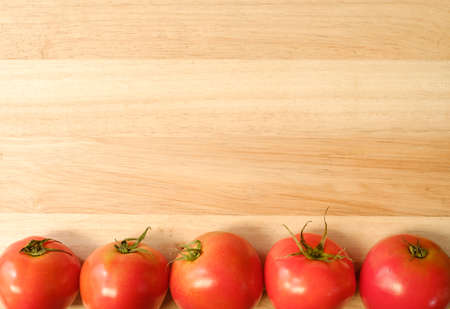 Wooden background with red tomatoes at the bottom