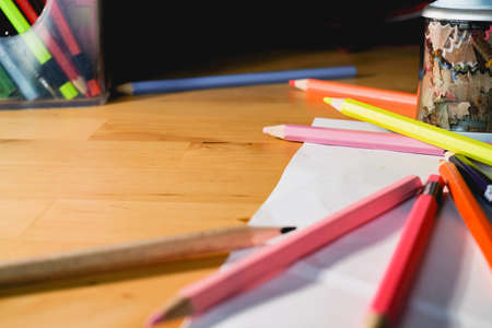 Color pencils on the wooden table with the light and copy space on left side. Creative design and...