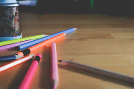 Color pencils on the wooden table with the light and copy space on right side. Creative design and...
