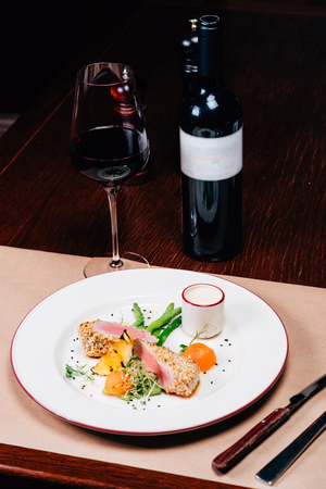dinner on the table, meat, a glass of red wine, a bottleの写真素材