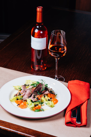 dinner on the table, salad, glass of pink wine, bottleの写真素材