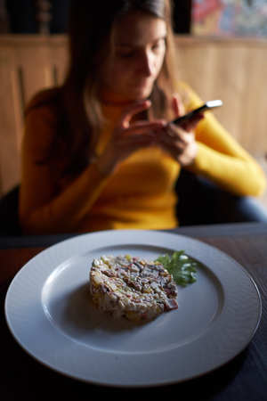 salad on a dish on the background of the girl sitting working in the phoneの写真素材