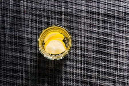 Slices of lemon inside a glass with water on a wooden table view from aboveの写真素材