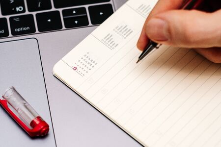 male hand encircles date 2 (two) in the diary calendar. on a laptop with a red pen