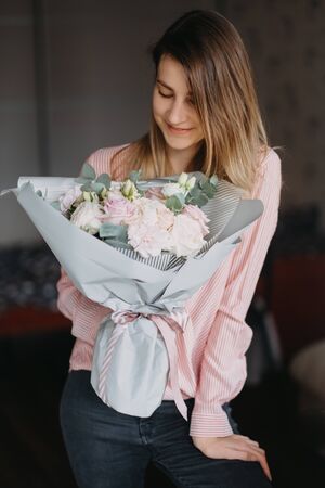 girl with a bouquet of flowers in her hands blonde hair in a pink shirt and black jeansの写真素材