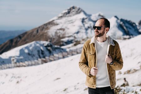 a man in glasses and a warm jacket on top of a snowy mountain of the Caucasus Mountainsの写真素材