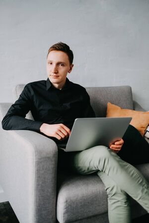 Handsome young man using laptop computer at home.の写真素材