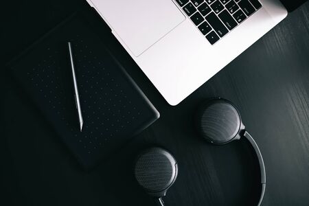 Dark modern workplace with a graphic tablet, laptop, wireless headphonesの写真素材