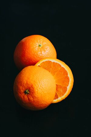 Vertical poster photo of an orange on a black background with light coming from topの写真素材