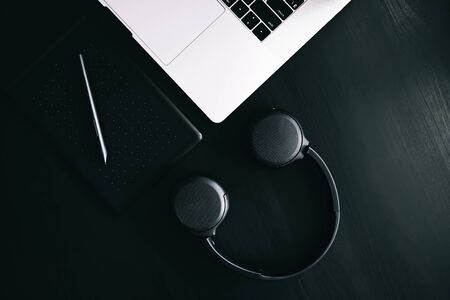 Dark modern workplace with a graphic tablet, laptop, wireless headphonesの写真素材