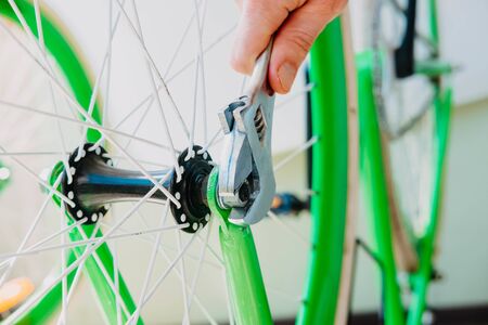 a man spins a wheel of a green bicycle with white wheelsの写真素材