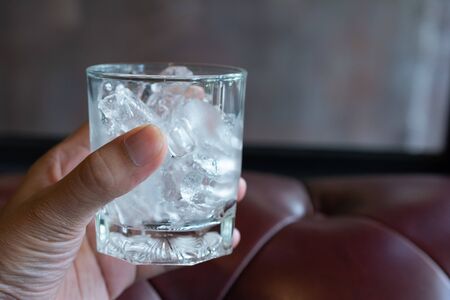 Ice cube in the glass with sofa wallpaper.の写真素材