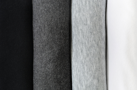 stack of black, grey and white (monochrome) t-shirt rolled up on white backgroundの写真素材