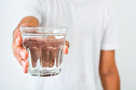 man's hand holding a glass of clean water on white background, health care conceptの写真素材