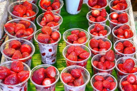 food stall, street food at walking street market, fresh strawberry in plastic cup for sale and ready for eat, Bangkok, Thailand (selective focus)の写真素材