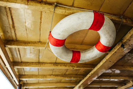 close up old red and white life buoy hanging on wooden ceiling of passenger boat, copy spaceの写真素材