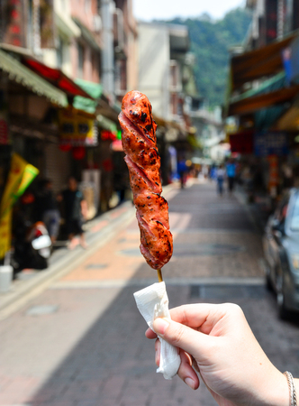 street food, hand holding grilled spicy pork sausage, Taiwanの写真素材
