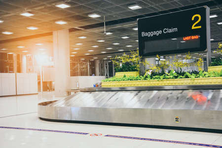 empty metal conveyor belt with baggage claim sign in arrival hall area at the modern airportの写真素材