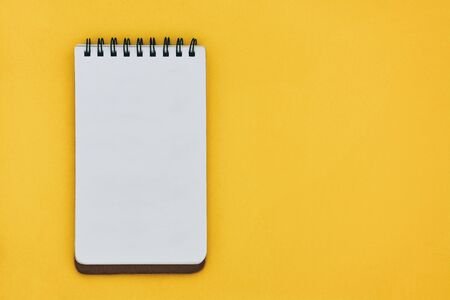 top view of empty open notebook on yellow background with copy space, flat lay