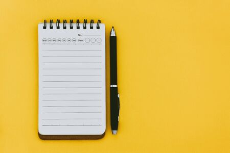top view of empty open lined notebook and pen on yellow background with copy space, flat lay