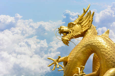 Chinese golden dragon statue on clouds and blue sky background, copy spaceの写真素材