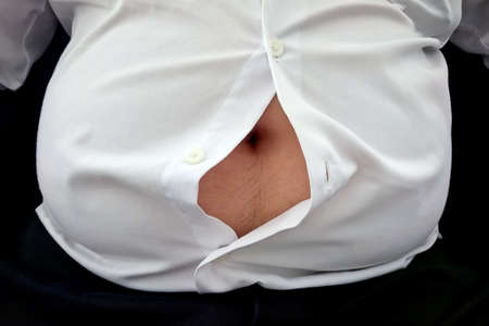 Fat man is big belly can not fasten his shirt buttonの写真素材