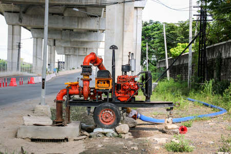 Mobile water pump is being pumped from the flooded area into the drain.の写真素材