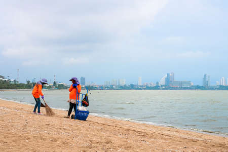 Chonburi, Thailand - April 29, 2018 : Two workers in orange shirt sweeping garbage to cleaning up on...