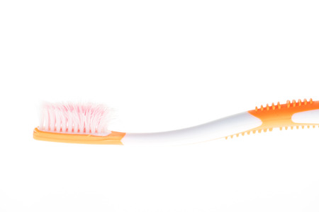 Orange worn toothbrush on white の写真素材