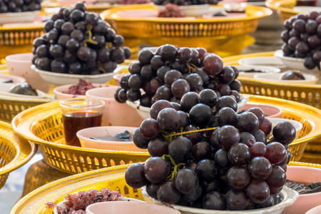 NAKORNPATHOM, THAILAND - JUL 5, 2014 : Grapes and many black thing to give to "Rahu" Thai God at Wat Sri Sa Thong. The Black Giant that eating the moon in historyのeditorial素材
