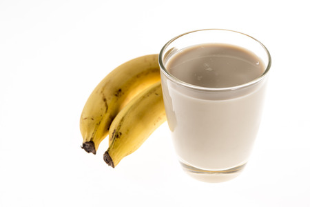 Two Natural Bananas beside a glass of milk isolated on white backgroundの写真素材