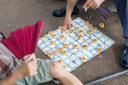 Senior playing chinese chess board game on the ground