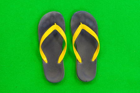 Black Rubber Slippers Placed on a green backgroundの写真素材