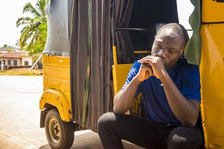 young african man feeling sad sitting in a rickshaw looking disturbed