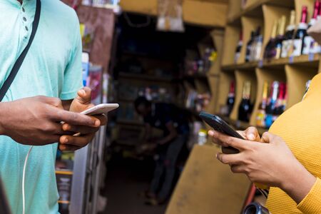 a young black man paying in a supermarket by doing a transfer with his mobile phone
