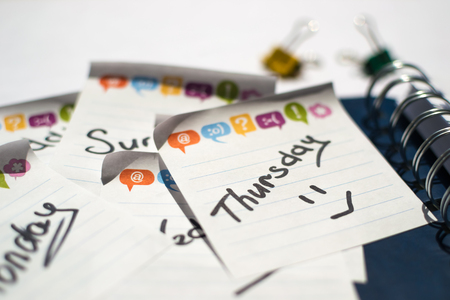 the name of the day of the week written on a sticky sheet in a blue notebook with springsの写真素材