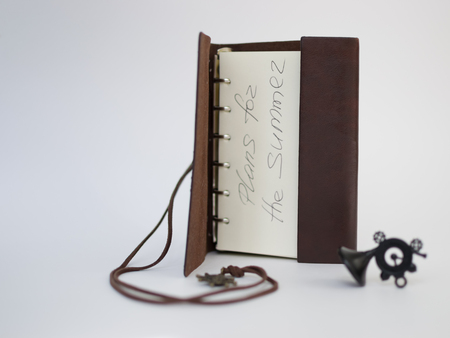 Handmade paper diary notebook in brown leather cover with over white backgroundの写真素材