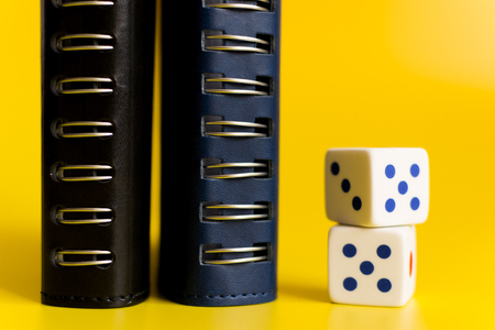 black and blue notebooks on a yellow background with white dice to calculate the betの写真素材